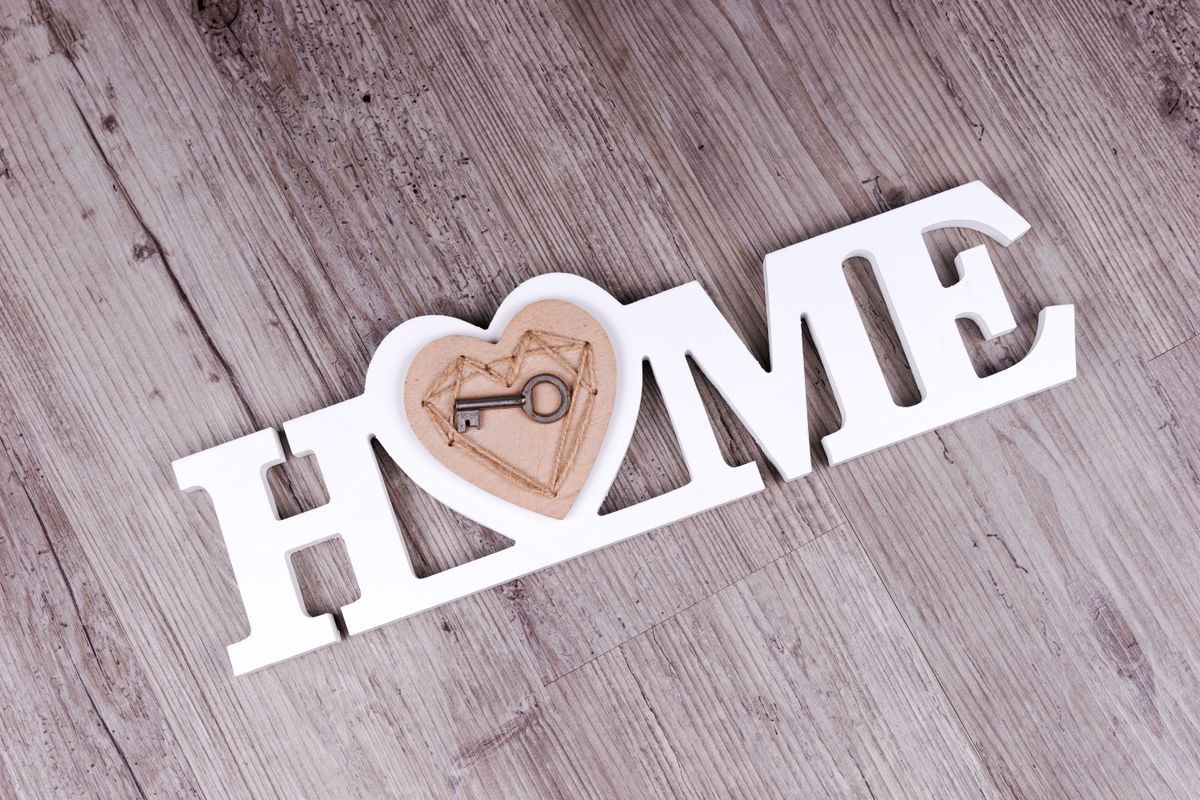 The key in the heart on the word Home in front of wooden background